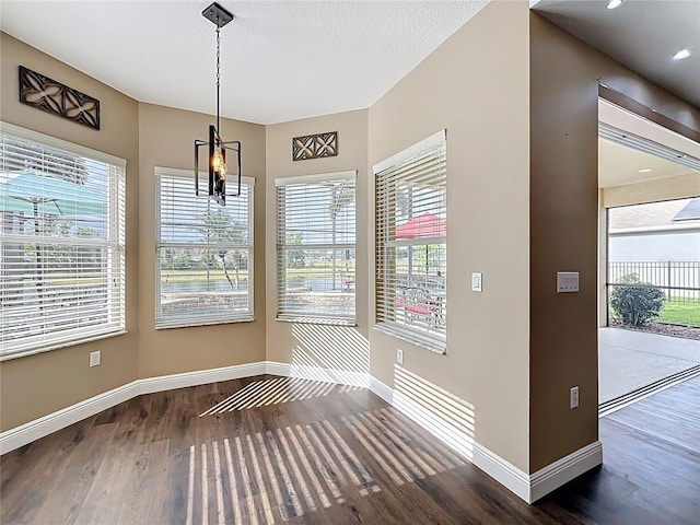 unfurnished dining area featuring wood finished floors, a healthy amount of sunlight, and baseboards