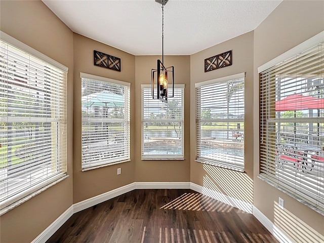 unfurnished dining area with baseboards and dark wood-style flooring