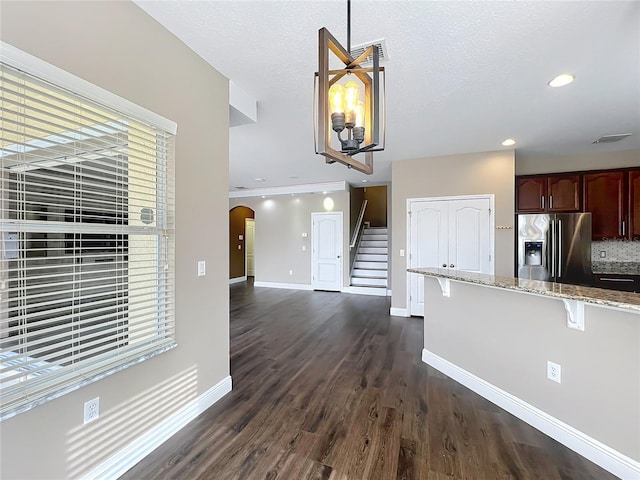 kitchen with a kitchen breakfast bar, arched walkways, stainless steel fridge, dark wood finished floors, and baseboards