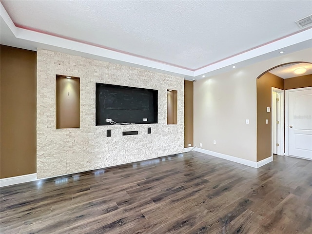 unfurnished living room with dark wood-style floors, arched walkways, visible vents, and a raised ceiling