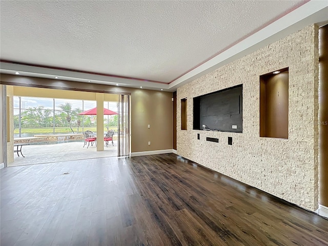 unfurnished living room featuring dark wood-type flooring, a textured ceiling, and baseboards