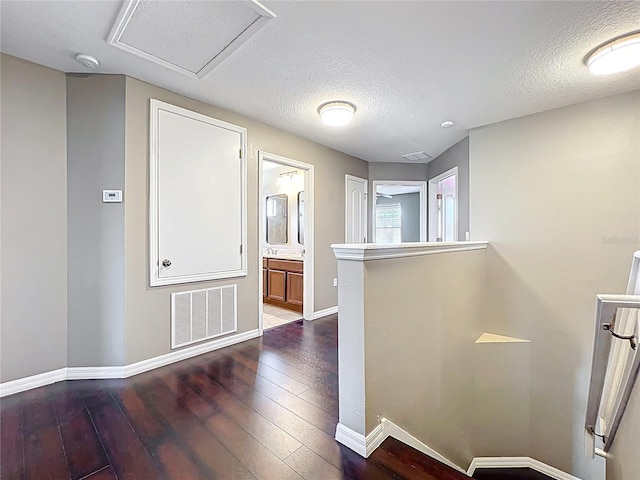 interior space featuring baseboards, visible vents, a textured ceiling, and dark wood-style floors