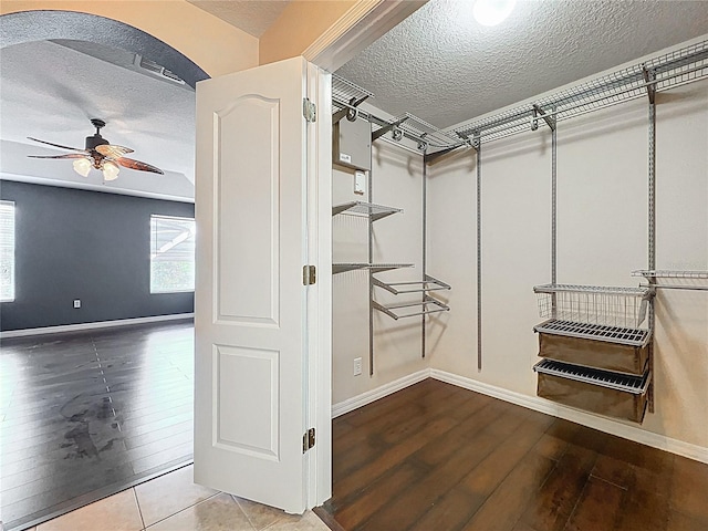 walk in closet with wood finished floors and a ceiling fan