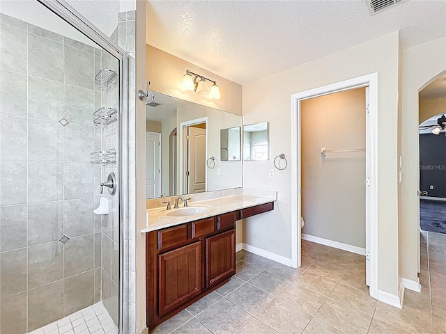full bath with tile patterned flooring, toilet, vanity, a textured ceiling, and a stall shower