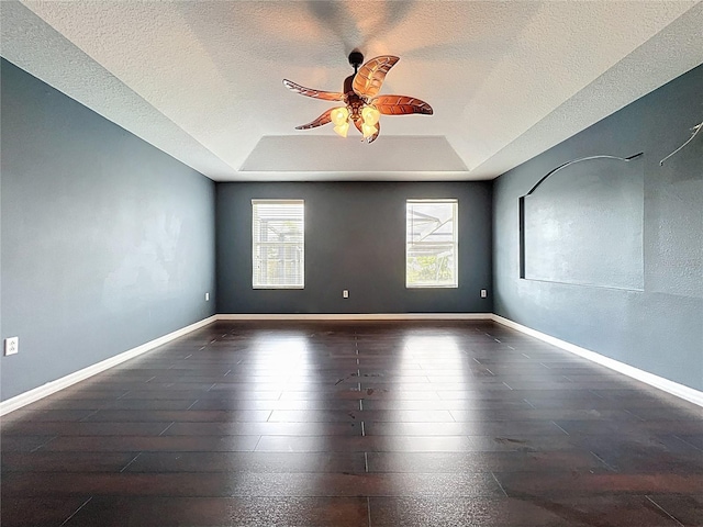 spare room with ceiling fan, baseboards, a textured ceiling, and a raised ceiling