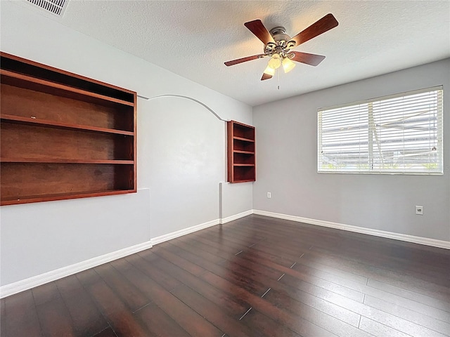 spare room featuring a textured ceiling, visible vents, dark wood-style floors, and ceiling fan