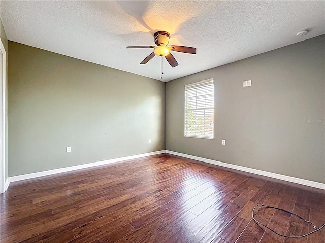 spare room with a ceiling fan, baseboards, a textured ceiling, and dark wood-style flooring