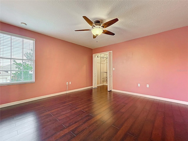 empty room featuring wood finished floors, a textured ceiling, a ceiling fan, and baseboards