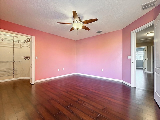 spare room with baseboards, wood finished floors, visible vents, and ceiling fan