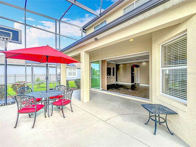 view of patio with a lanai, outdoor dining area, and fence