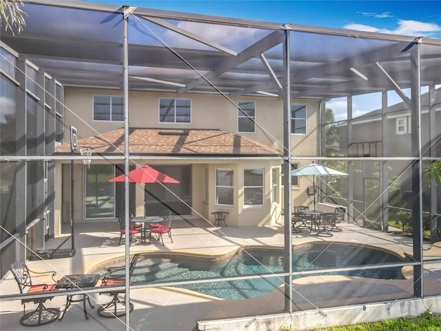 rear view of house with a patio area, a lanai, an outdoor pool, and stucco siding