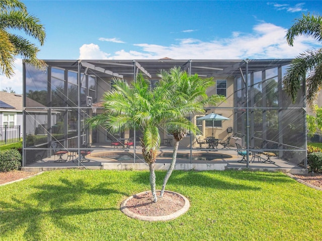rear view of property featuring glass enclosure, a patio area, a lawn, and an outdoor pool