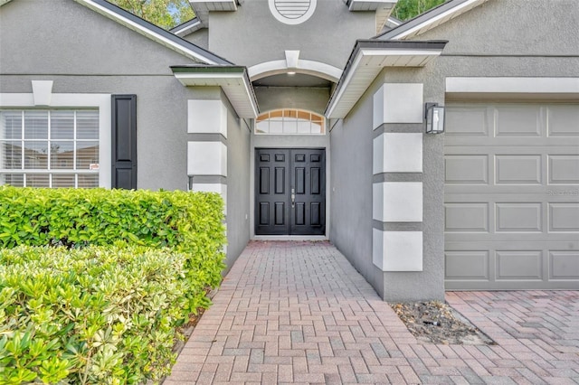 doorway to property featuring a garage and stucco siding