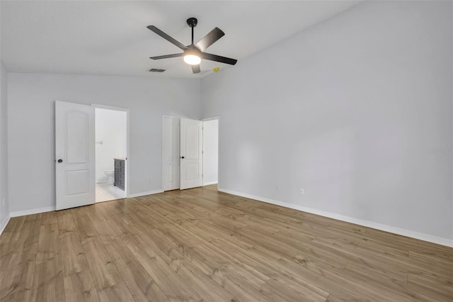 unfurnished bedroom with visible vents, baseboards, light wood-type flooring, and vaulted ceiling