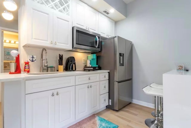 8800 Bay Pines Blvd Unit 306, Saint Petersburg, FL 33709 - kitchen with a sink, light wood-type flooring, visible vents, white cabinetry, and appliances with stainless steel finishes