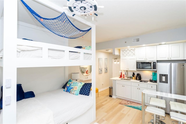 8800 Bay Pines Blvd Unit 306, Saint Petersburg, FL 33709 - bedroom featuring ensuite bathroom, a sink, light wood-style floors, stainless steel fridge with ice dispenser, and visible vents