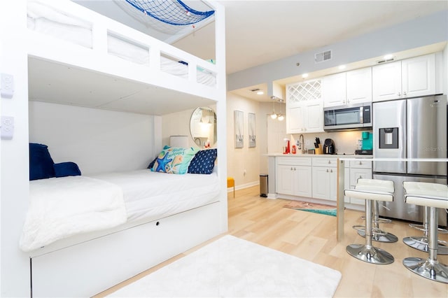 8800 Bay Pines Blvd Unit 306, Saint Petersburg, FL 33709 - bedroom featuring light wood finished floors, visible vents, a sink, and stainless steel fridge with ice dispenser