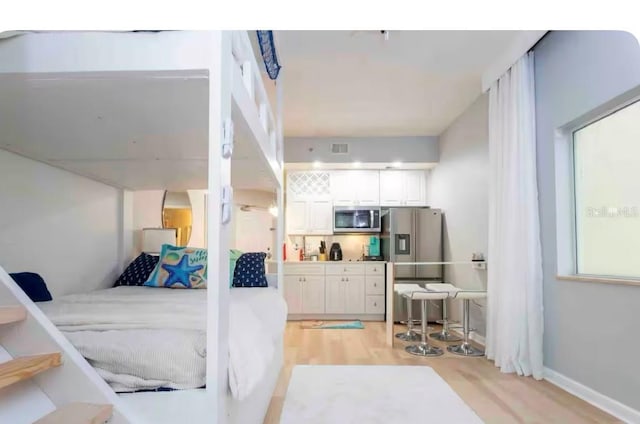 8800 Bay Pines Blvd Unit 306, Saint Petersburg, FL 33709 - bedroom featuring light wood finished floors, visible vents, stainless steel refrigerator with ice dispenser, and baseboards
