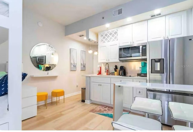 8800 Bay Pines Blvd Unit 306, Saint Petersburg, FL 33709 - kitchen with white cabinetry, appliances with stainless steel finishes, light wood-style floors, and visible vents