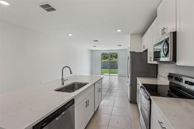 1839 Brekey Way, Zephyrhills, FL 33541 - kitchen featuring appliances with stainless steel finishes, a sink, recessed lighting, light tile patterned floors, and white cabinetry