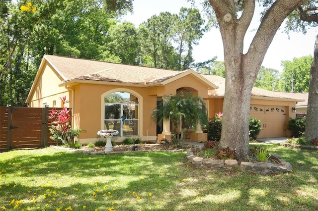 single story home featuring a gate, a front lawn, an attached garage, fence, and stucco siding