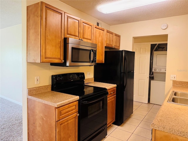 1695 Lee Rd Unit E214, Winter Park, FL 32789 - kitchen featuring black range with electric cooktop, stacked washing machine and dryer, stainless steel microwave, light countertops, and a textured ceiling