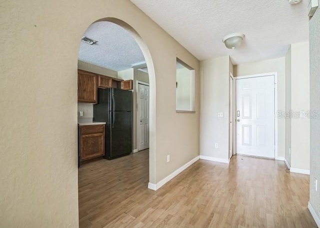 2503 SE 18th Cir, Ocala, FL 34471 - kitchen featuring light wood-style flooring, freestanding refrigerator, arched walkways, and a textured ceiling