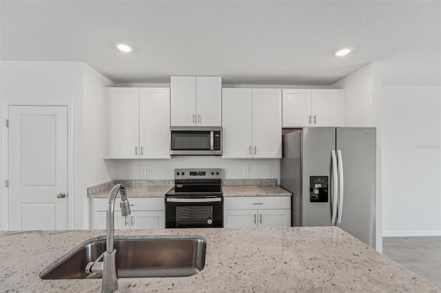 1861 Brekey Way, Zephyrhills, FL 33541 - kitchen featuring appliances with stainless steel finishes, a sink, white cabinetry, light stone counters, and recessed lighting