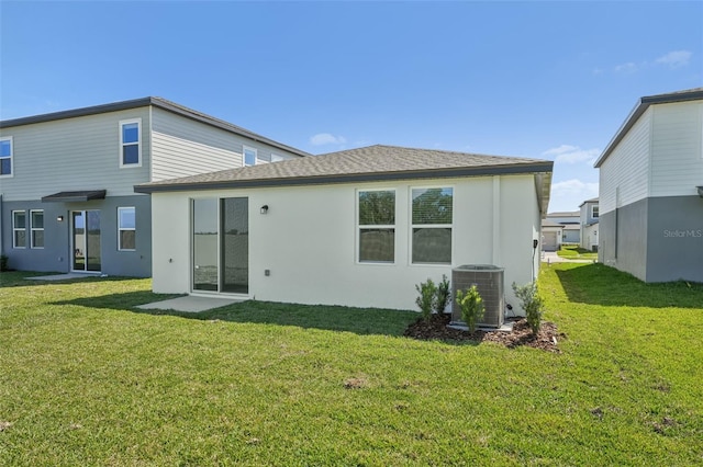 1861 Brekey Way, Zephyrhills, FL 33541 - rear view of house featuring a lawn, central air condition unit, stucco siding, and a shingled roof