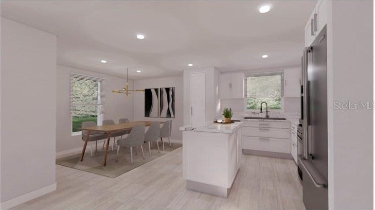 kitchen featuring white cabinets, a center island, a sink, and light wood-type flooring