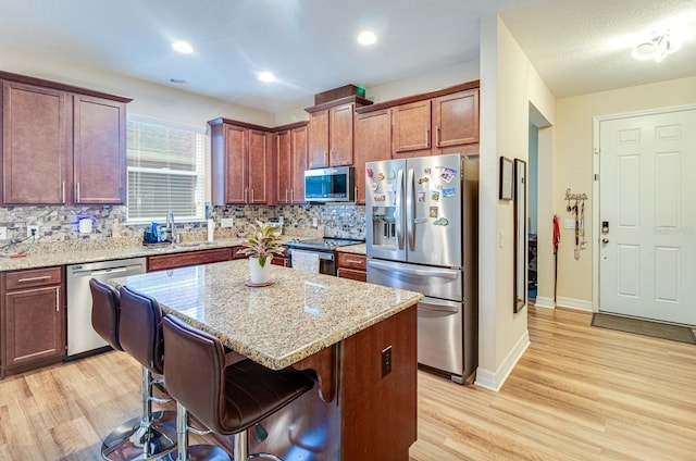 2331 Kennington Cv, Deland, FL 32724 - kitchen with decorative backsplash, appliances with stainless steel finishes, a kitchen breakfast bar, and light wood-style floors