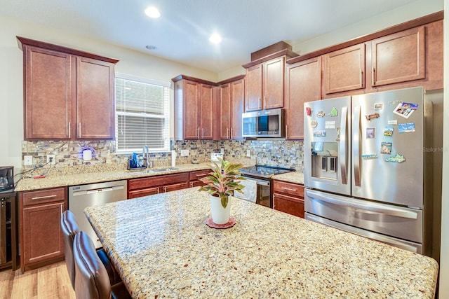 2331 Kennington Cv, Deland, FL 32724 - kitchen featuring a center island, a sink, decorative backsplash, light stone countertops, and appliances with stainless steel finishes
