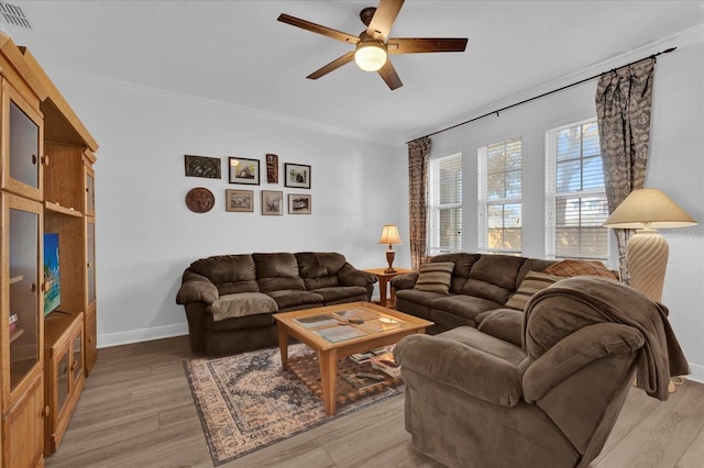 living room featuring ceiling fan, visible vents, baseboards, and light wood-style flooring
