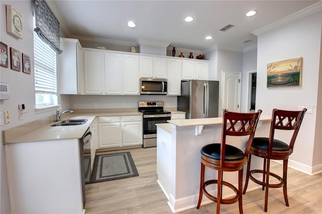 kitchen with crown molding, a sink, a breakfast bar area, stainless steel appliances, and visible vents