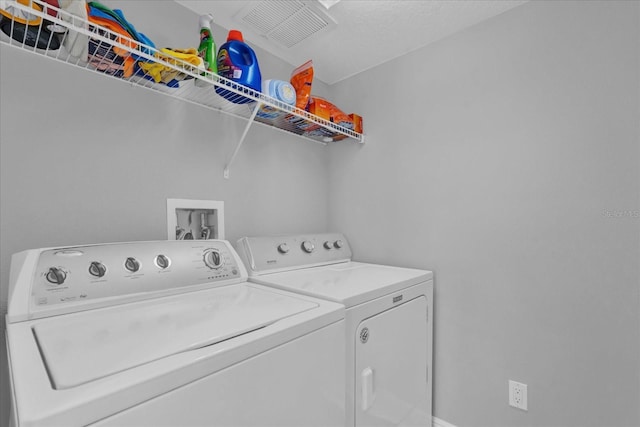 washroom with laundry area, separate washer and dryer, and visible vents