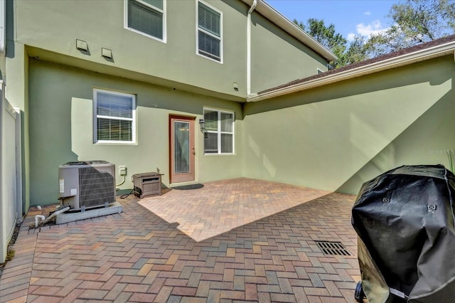rear view of property with central AC unit, a patio area, and stucco siding