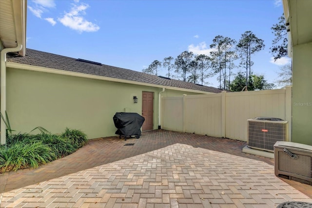 view of patio featuring fence, cooling unit, and grilling area