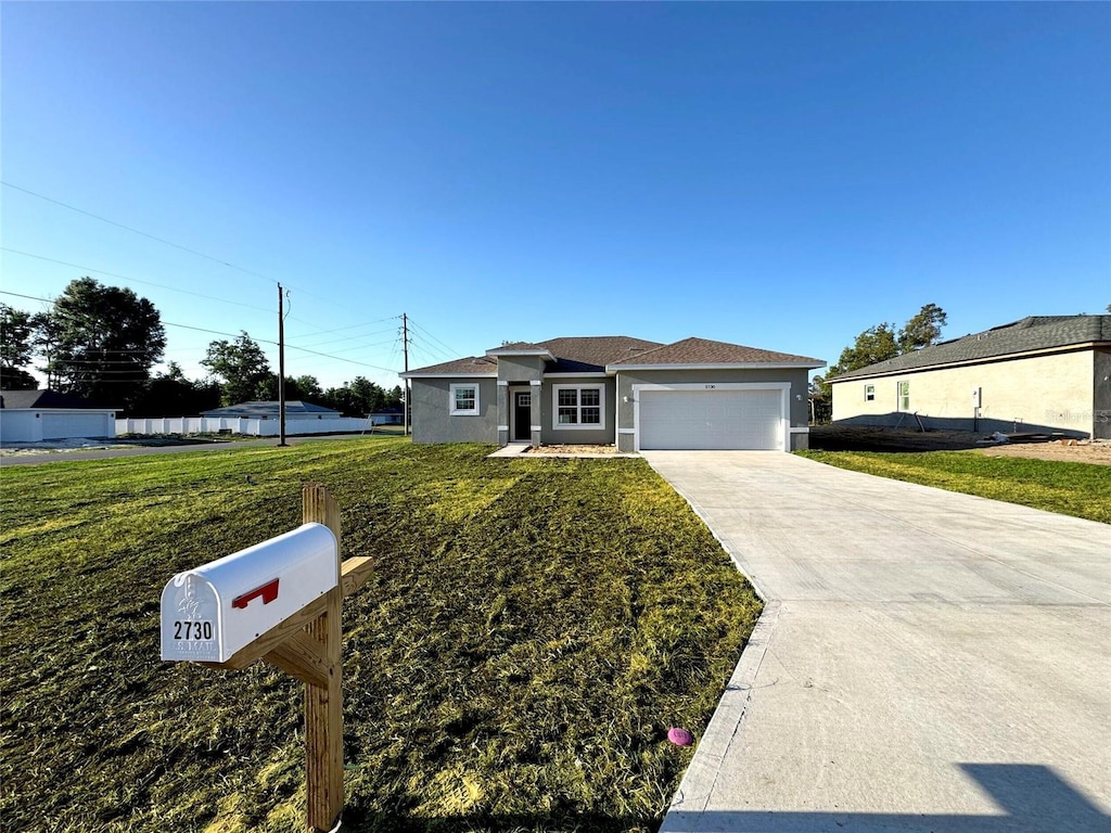 ranch-style house with a garage, driveway, stucco siding, and a front lawn