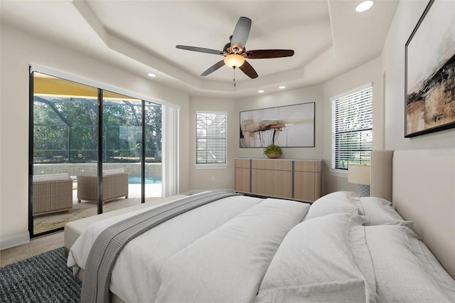 carpeted bedroom with a ceiling fan, a tray ceiling, recessed lighting, and access to exterior