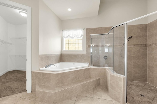 full bath with a bath, tile patterned flooring, a shower stall, and a spacious closet