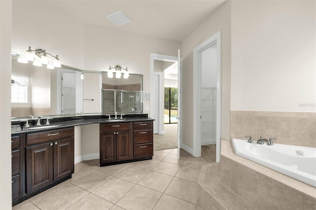 full bathroom featuring a stall shower, tile patterned flooring, a garden tub, vanity, and a walk in closet