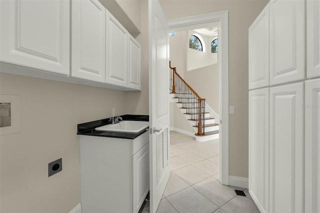 laundry room featuring cabinet space, hookup for an electric dryer, baseboards, and light tile patterned floors
