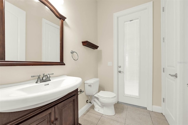bathroom with toilet, baseboards, vanity, and tile patterned flooring