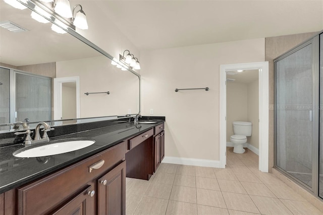 bathroom with double vanity, toilet, a stall shower, a sink, and tile patterned floors