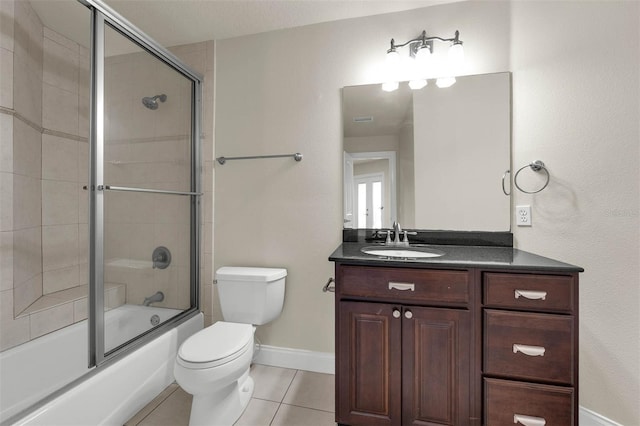 bathroom featuring toilet, vanity, tile patterned floors, combined bath / shower with glass door, and baseboards