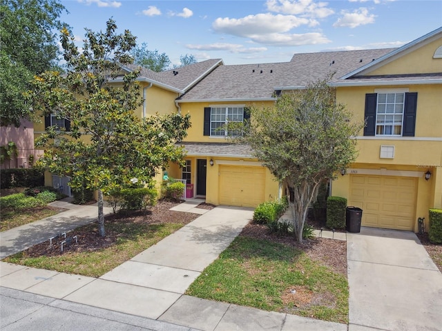 view of property featuring a garage, concrete driveway, and stucco siding