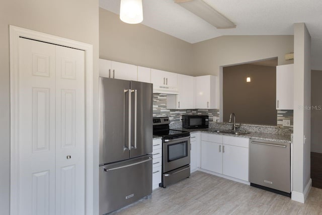 3004 Cottage Grove Ct Unit 1805, Orlando, FL 32822 - kitchen featuring appliances with stainless steel finishes, under cabinet range hood, lofted ceiling, tasteful backsplash, and white cabinetry