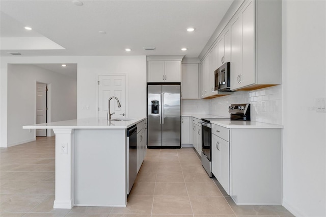 10008 Last Light Gln, Parrish, FL 34219 - kitchen with light tile patterned floors, appliances with stainless steel finishes, backsplash, and a center island with sink