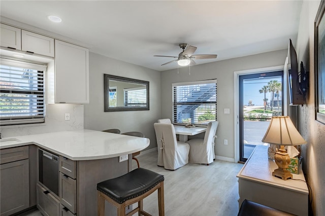 865 Ladyfish Ave Unit C104, New Smyrna Beach, FL 32169 - kitchen with a ceiling fan, a kitchen breakfast bar, gray cabinets, light wood-style flooring, and a peninsula