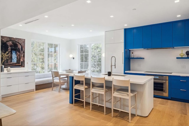 kitchen with stainless steel oven, modern cabinets, a sink, and visible vents